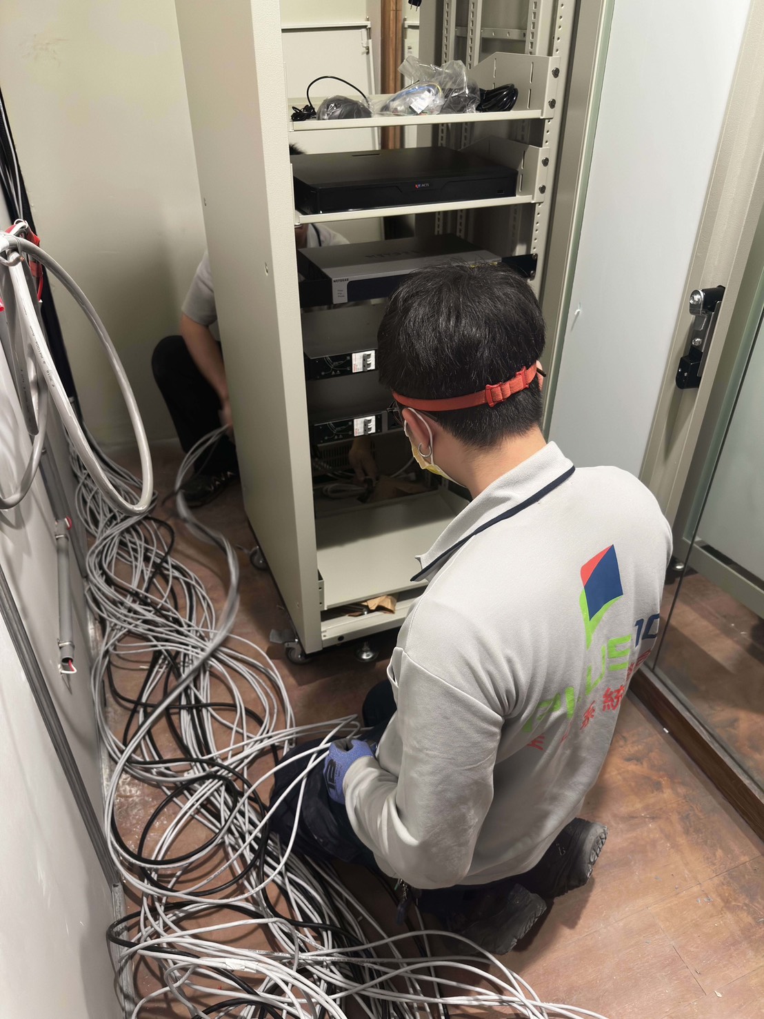 佳實工程人員於機櫃內架設監視器主機與網路設備，串接弱電線路